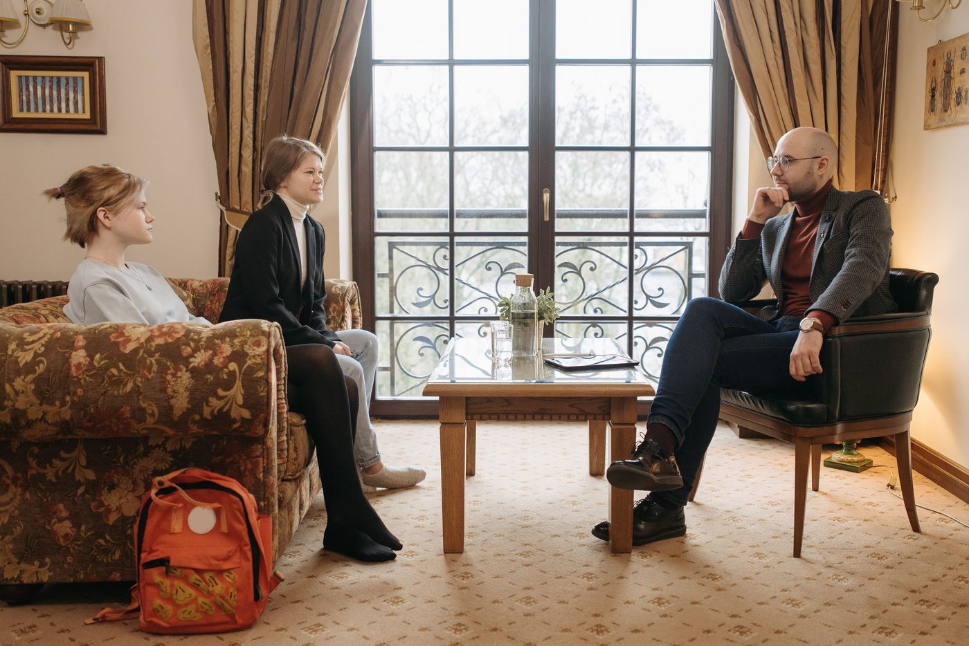 A parent and child meeting with a professional in a formal setting